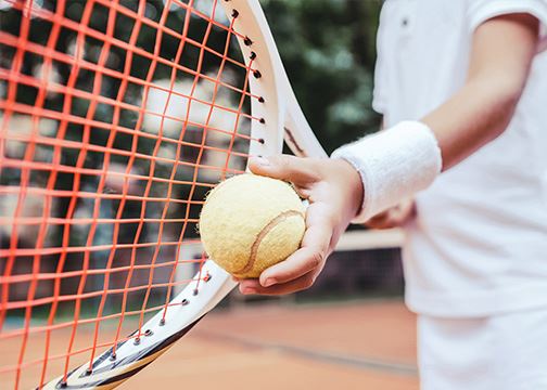 Image of kid holding tennis ball and racquet 